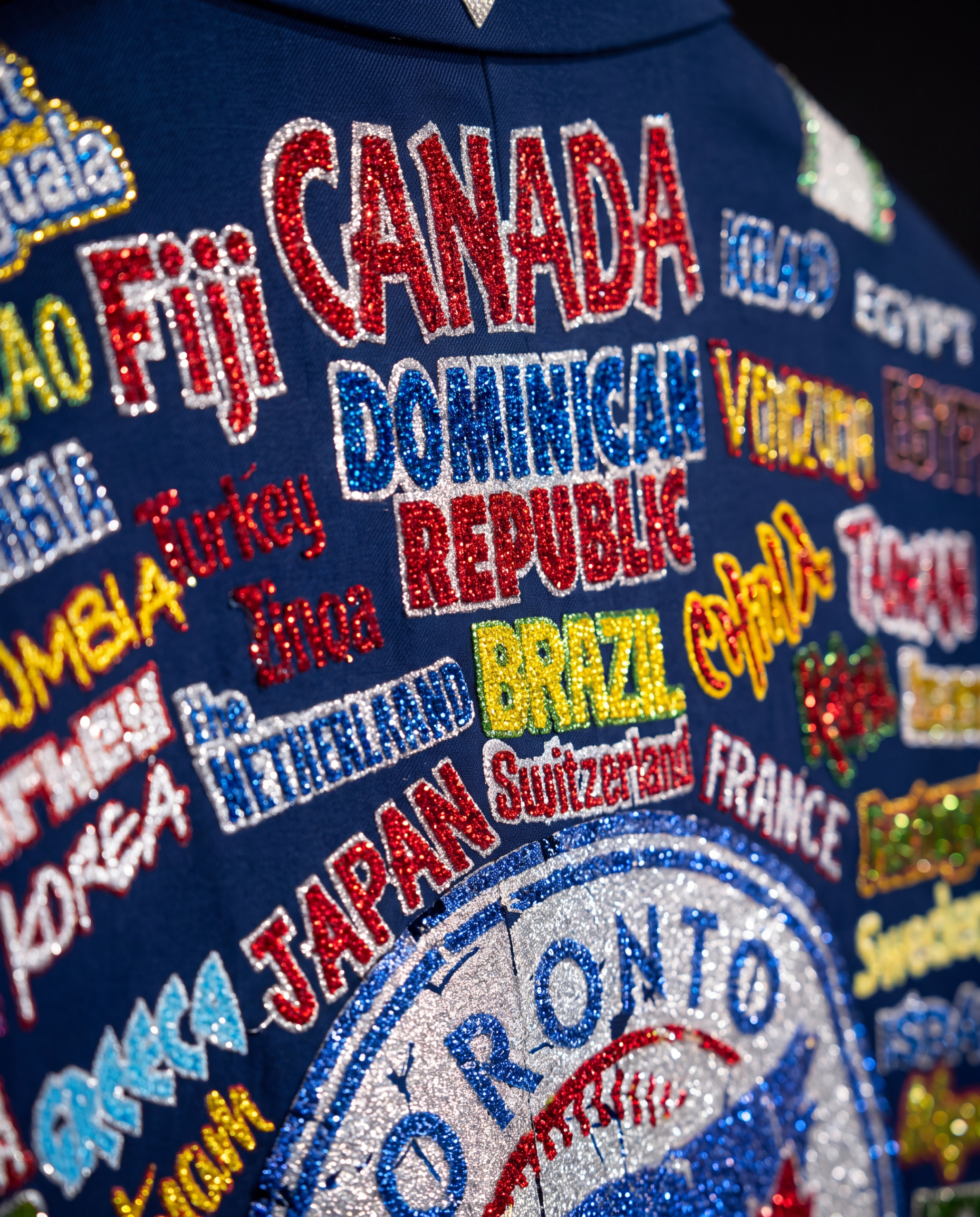 Macro close-up of hand-beaded country names across the back of the blazer